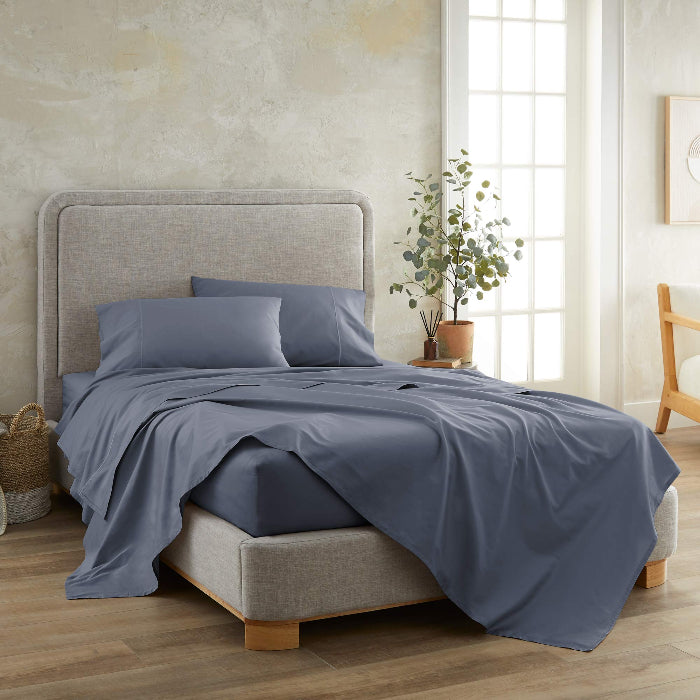 Blue organic sateen sheet set bedding set on a bed in a bedroom with a neutral color scheme.