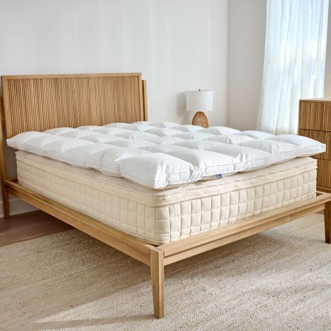 Wooden bed with white  latex mattress topper in a bedroom setting
