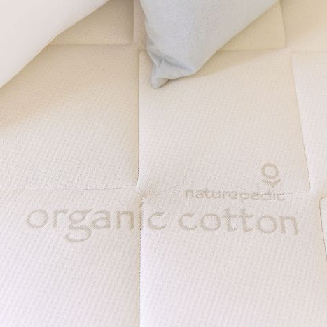 Close-up of an organic cotton mattress 'Naturepedic' branding.