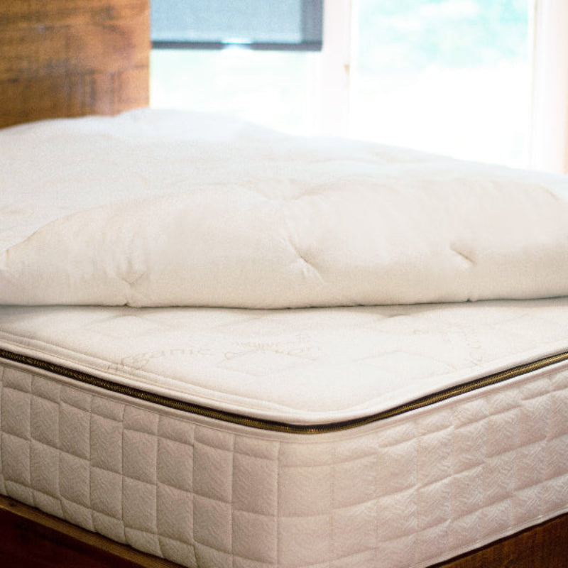 Wooly 3" Organic Wool Mattress Topper on a bed in a room with windows.