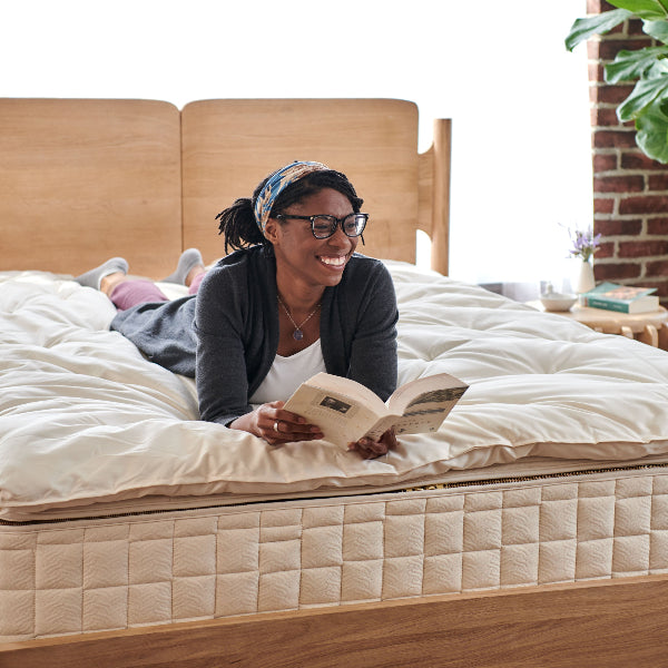 Person reading a book on a Wooly 3" Organic Wool Mattress Topper on a bed