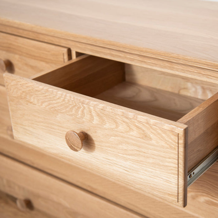 Wooden drawer being pulled out from a wooden kids chest of drawers