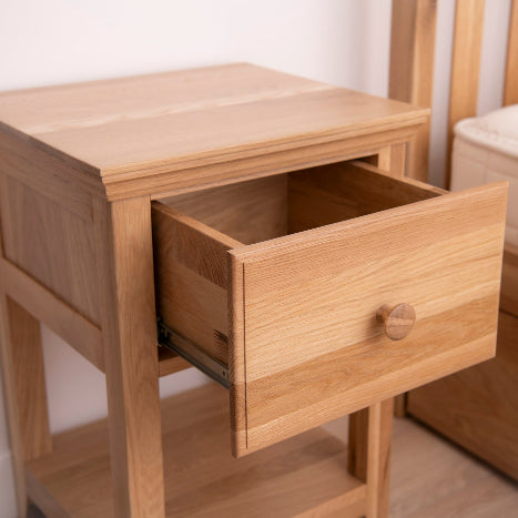 Wooden nightstand with open drawer in a bedroom setting