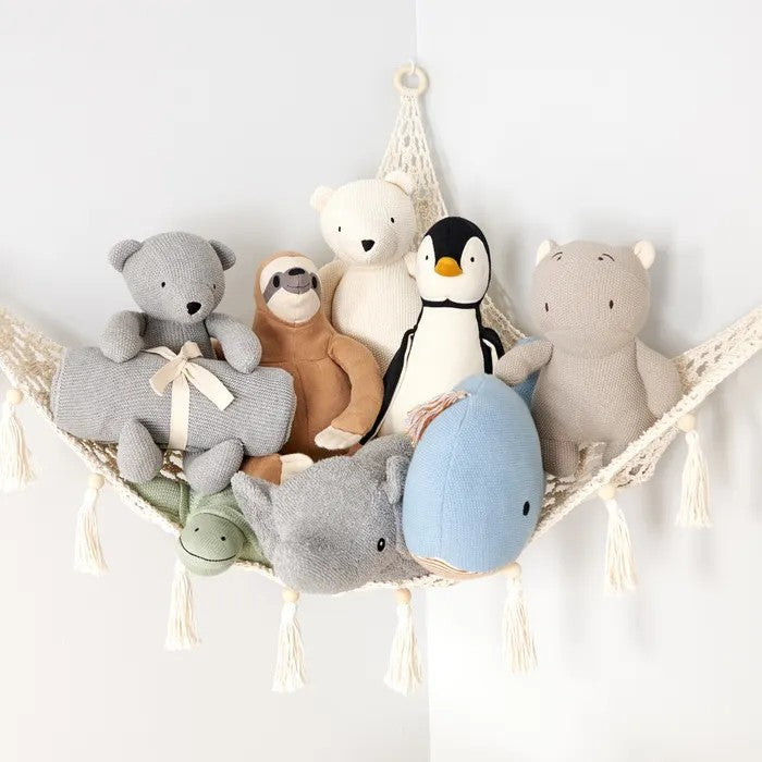 Collection of organic soft toys including bears, a penguin, and a dolphin on a hammock against a white background.