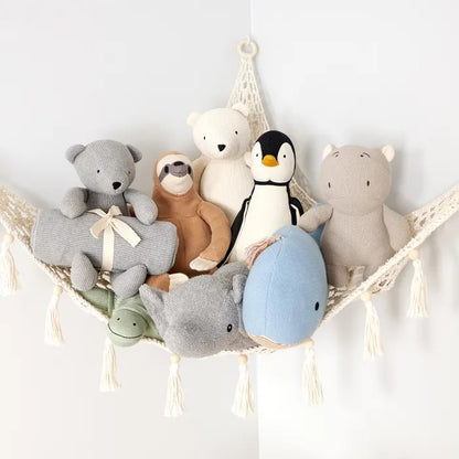 Collection of organic soft toys including bears, a penguin, and a dolphin on a hammock against a white background.