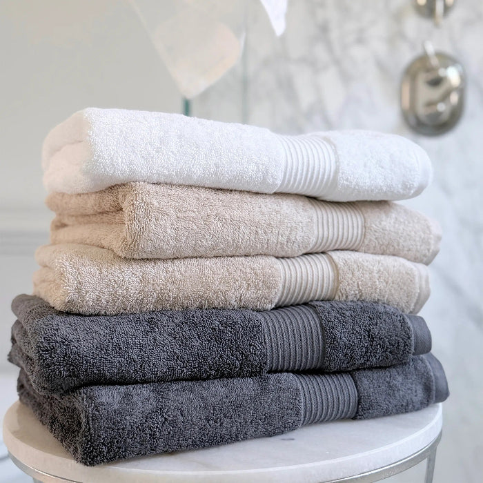 Stack of folded organic cotton towels on a round white table with a neutral background