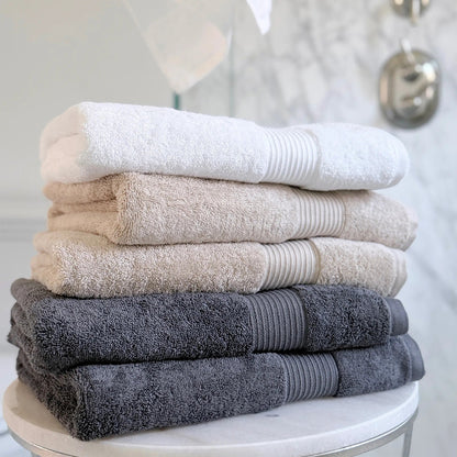 Stack of folded organic cotton towels on a round white table with a neutral background