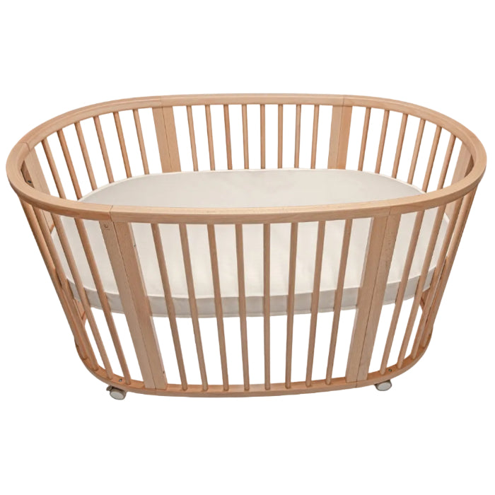 Wooden crib with a white mattress on a white background