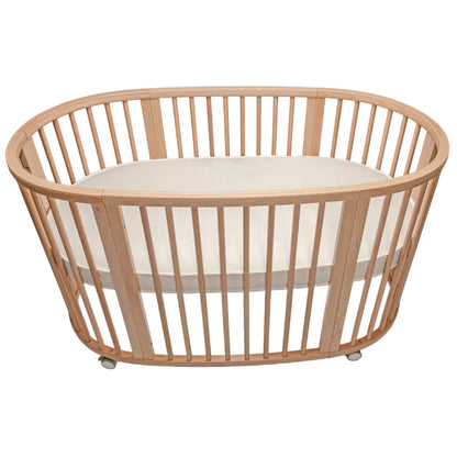 Wooden crib with a white mattress on a white background